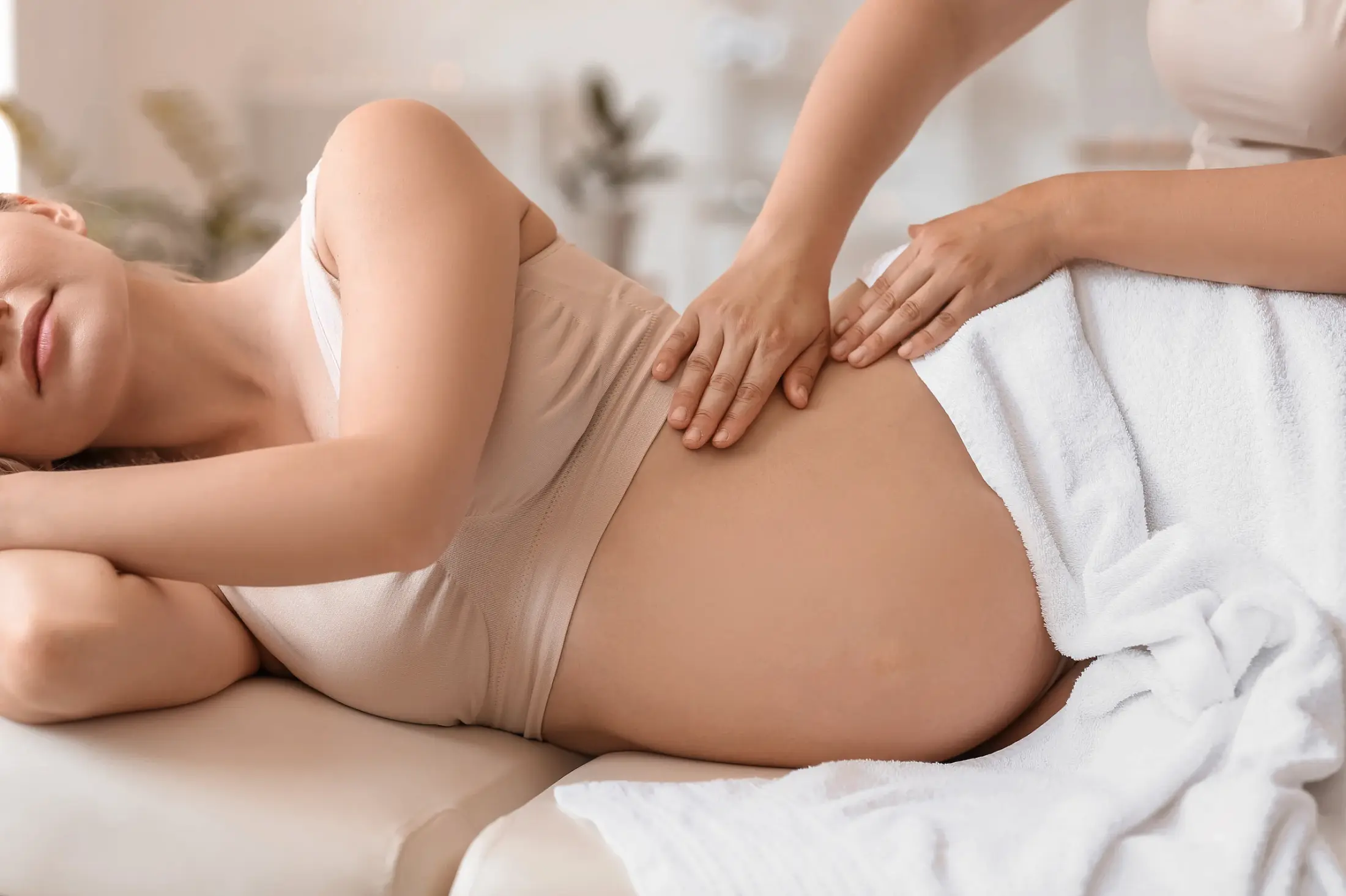 Schwangere Frau in Seitenlage erhält eine sanfte Rückenmassage – Schwangerschaftsmassage im Massage Zentrum Bülach